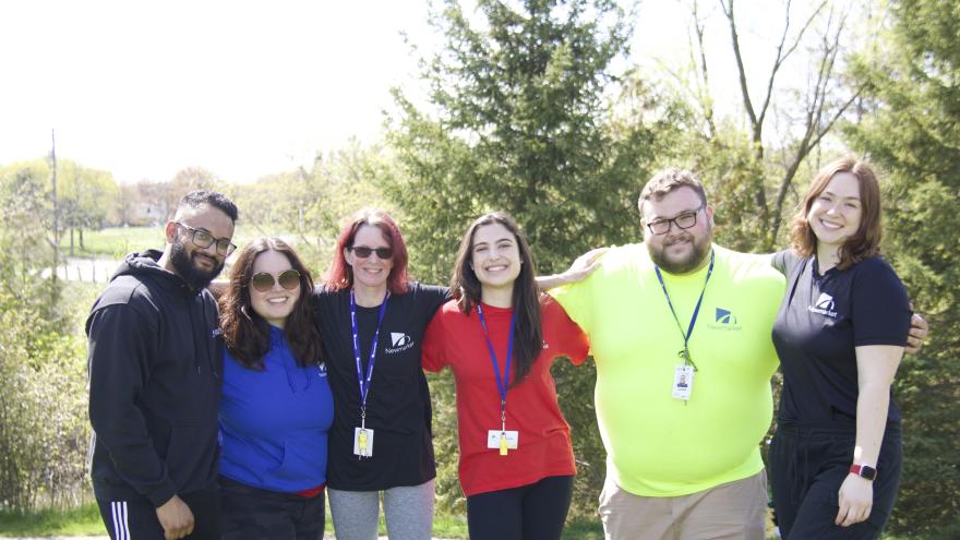 People standing arm in arm on a grassy area outdoors