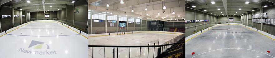 Spacious indoor ice rink, bright overhead lights, empty and clean.